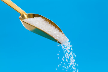 Sugar crystals falling out of steel scoop