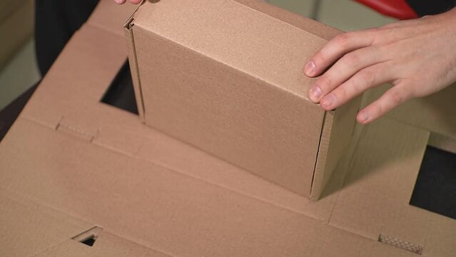the man himself folds the cardboard box according to the brochure in order to pack the finished product into it. view from above. High-quality Full HD video recording. slow motion video
