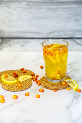 Sea buckthorn tea with lemon and berries in a glass
