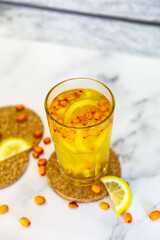 Sea buckthorn tea with lemon and berries in a glass