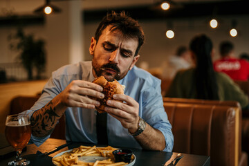 Man in a business shirt and tie with rolled up sleeves sitting in the pub, holding and enjoying a...