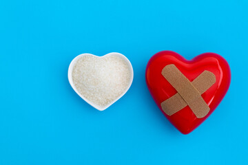 Red heart with bandage and a bowl of granulated sugar