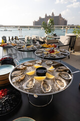 Oysters on metal tray with ice, lemon Restaurant menu, dieting, cookbook recipe. Expensive meal. Healthy food, gourmet, raw sea ocean. professional chef cooks set seafood sauce Cooking mediterranean