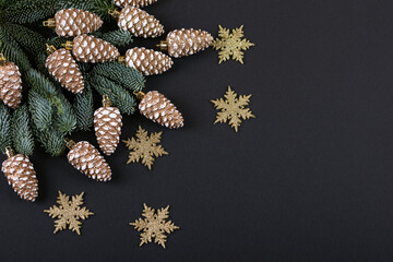 Green branches of a Christmas tree with decorations in the form of golden cones and snowflakes on a...