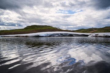 Summer landscape. Small lake covered with ice. Kamchatka