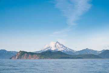 Summer landscape of the coastline with snow covered volcano. Kamchatka