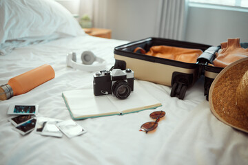 Hotel, travel and bedroom with a suitcase, camera and pictures on bed on holiday, vacation or trip....