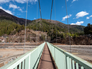 Fototapeta na wymiar 冬晴れの山梨県丹波山村の丹波川にかかるやまびこ橋
