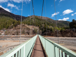 Obraz premium 冬晴れの山梨県丹波山村の丹波川にかかるやまびこ橋