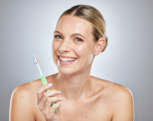 Obraz premium Face, teeth and woman with toothbrush in studio isolated on a gray background. Oral health, dental veneers and female model getting ready to brush with toothpaste for hygiene, cleaning and wellness.