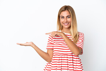 Blonde Uruguayan girl isolated on white background holding copyspace imaginary on the palm to...