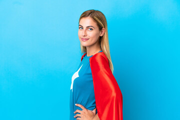 Blonde woman over isolated background in superhero costume and doingposing with arms at hip and smiling © luismolinero