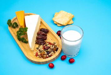 Blue background for holidays Shavuot, Pentecost. Milk, homemade cheese, nuts and berries, bread and dates on a wooden tray.