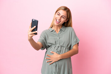 Young Uruguayan woman isolated on blue background pregnant and making a selfie