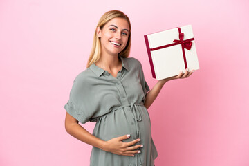 Young Uruguayan woman isolated on blue background pregnant and holding a gift