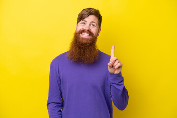 Redhead man with beard isolated on yellow background showing and lifting a finger in sign of the best