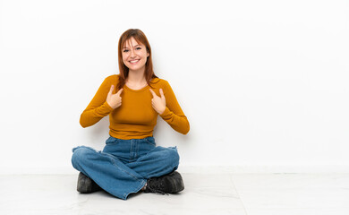 Fototapeta na wymiar Redhead girl sitting on the floor isolated on white background with surprise facial expression