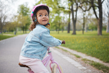 Kids, bike and learning to ride with a girl in the park on her bicycle while wearing a helmet for...