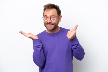 Fototapeta premium Middle age caucasian man isolated on white background holding copyspace imaginary on the palm to insert an ad and with thumbs up
