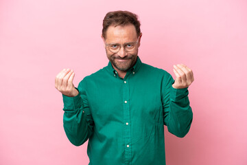 Middle age caucasian man isolated on pink background making money gesture