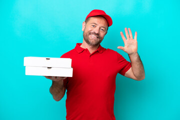 Pizza delivery man with work uniform picking up pizza boxes isolated on blue background counting five with fingers