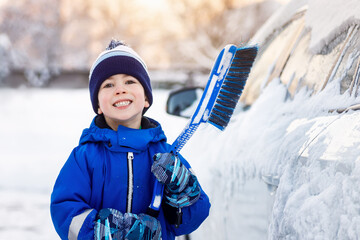 little boy with brush for cleaning snow from car
