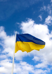 yellow and blue flag of Ukraine and sky with clouds in background