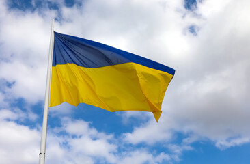 yellow and blue flag of Ukraine and sky with clouds in background