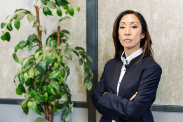 Confident Chinese businesswoman near potted plant