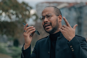 latin man talking on mobile phone with hands free or sending voice message