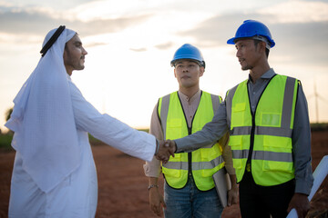 Asian Engineers and Arab businessman checking and inspecting on construction with sunset sky....