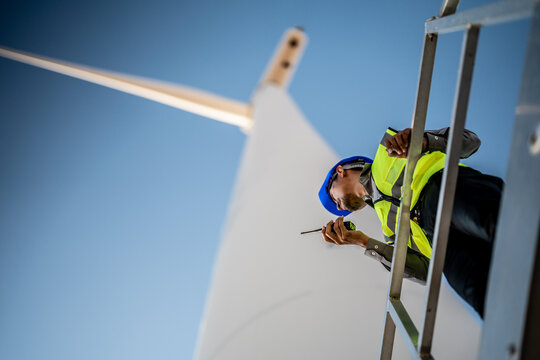 Asian engineers working in fieldwork outdoor. Workers check and inspect construction and machine around building project site. Wind turbine for electrical of clean energy and environment sustainable.