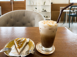 Iced caramel cappuccino and mango cheesecake at cafe table. Sweet dessert concept