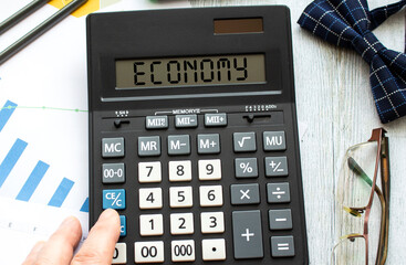 A calculator labeled ECONOMY lies on financial documents in the office. Business concept