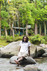 A Man With Locks Hair Wearing White Shirt Posing Near a River in the Nature