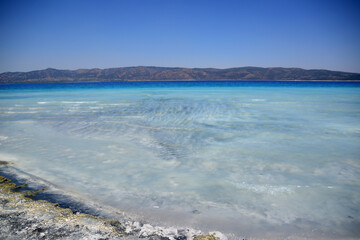 Fototapeta na wymiar coastline with clear blue water and hills on background in sunny day