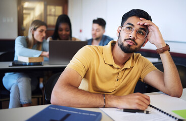 Indian man, student and bored in classroom, tired and stress with notes, examination or task. Young male, guy or exhausted for education, test or notes for assignment with headache and depressed