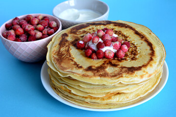 heap of fried blini isolated on plate with frozen wild strawberries