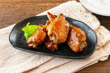 黒い皿に盛った手羽の照り焼き