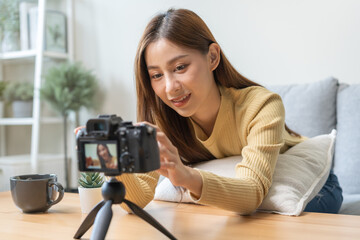 Vlogger influencer, attractive asian young woman blogger, content maker looking at camera, recording interview sit on sofa, talk on video shooting social media, live broadcast with technology at home.