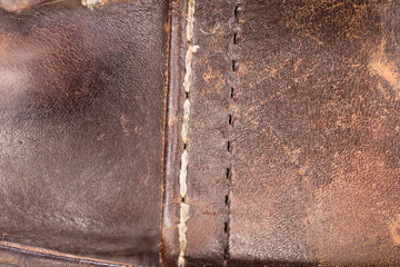 Old brown leather with a sewn seam.