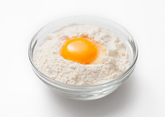 Bowl plate with flour and egg yolk on white background.