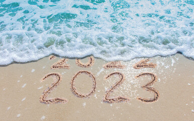 Message Year 2022 replaced by 2023 written on beach sand background. Good bye 2022 hello to 2023 happy New Year coming concept. - obrazy, fototapety, plakaty