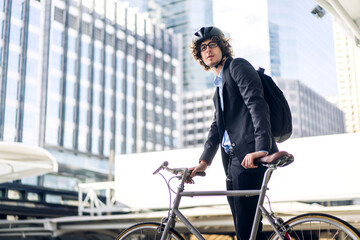 Portrait of hipster handsome businessman in suit with backpack looking forward while commuting riding bicycle on the street city way go to work.business travel transport bike concept
