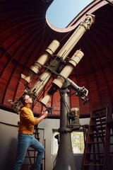 Astronomer with a big astronomical telescope in observatory doing science research.