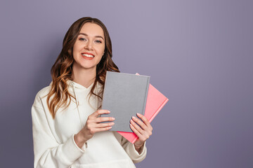 Ukrainian student girl smiles and holds books on a dark gray background copy space