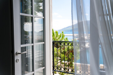 Balcony with sea view. Big window and opened door in authentic house on coastline. Cozy home...