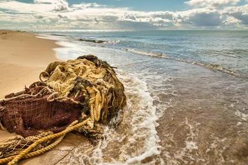 Foto op Plexiglas A pick fishing net washed up on the seashore. A tangled net lies on a sandy beach. Baltic sea, Hel Peninsula, Pomerania, Hel, Poland © krysek