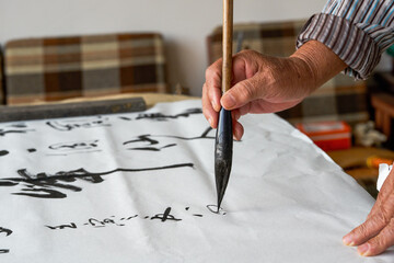 An old Chinese calligrapher is writing calligraphy characters, creating calligraphy works - obrazy, fototapety, plakaty
