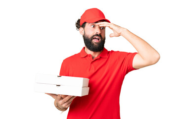 Pizza delivery man with work uniform picking up pizza boxes over isolated chroma key background doing surprise gesture while looking to the side